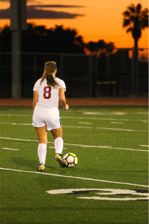 Madeleine Espinoza '20 with the ball as the sun sets in the background. Credit: Jason Messner / The Foothill Dragon Press