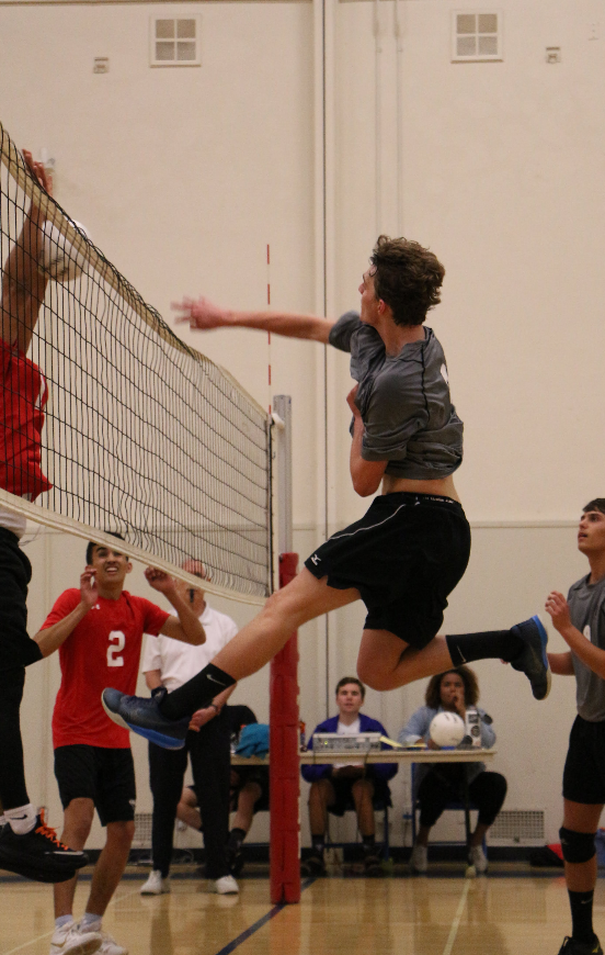 Tanner Nodolf '18 hits the ball over the net towards the blockers. Credit: Jason Messner / The Foothill Dragon Press