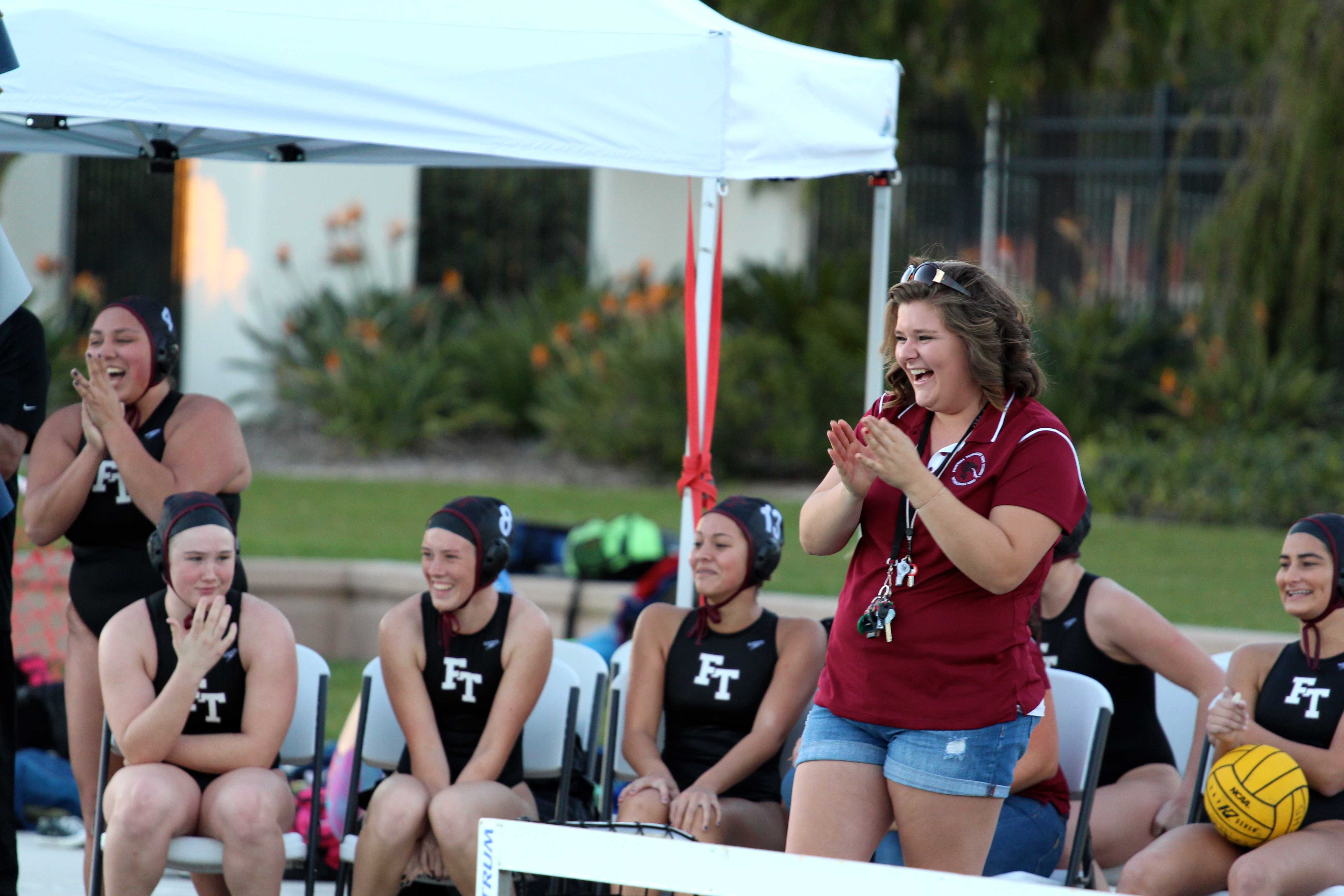 Samantha Ebberson (standing) applauds with Foothill Technology's inaugural girl's water polo team. Credit: Kazu Koba/The Foothill Dragon Press