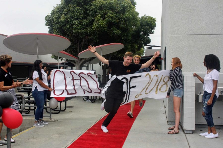 Cole Chilcutt 18 bursts through the banner on his way to the senior flash mob. Credit: Gabrialla Cockerell / The Foothill Dragon Press