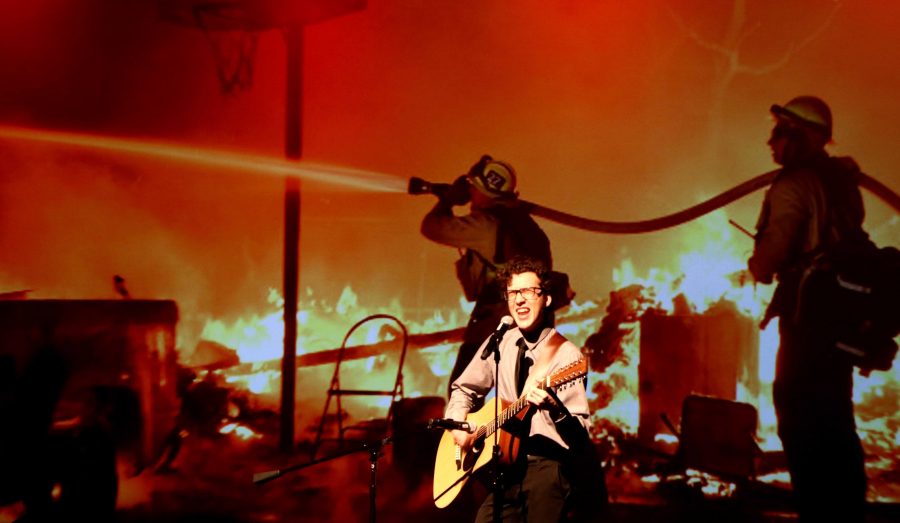 Jake Needham sings My Hero by the Foo Fighters standing in front of images of the Thomas Fire Firefighters. Credit: Abigail Massar / The Foothill Dragon Press