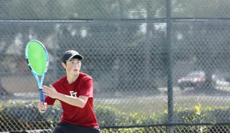 Benjamin Wang 23 raises his racket to intercept the ball.