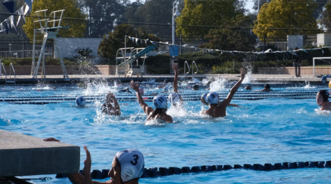 The boys water polo team strategically setting up a shot that the opposing team, Villanova, is unable to block.