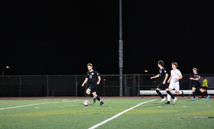 Number 17, Tyler Reeder 22, sprints down the field in hopes of scoring a goal while his teammates and opponents follow close behind.