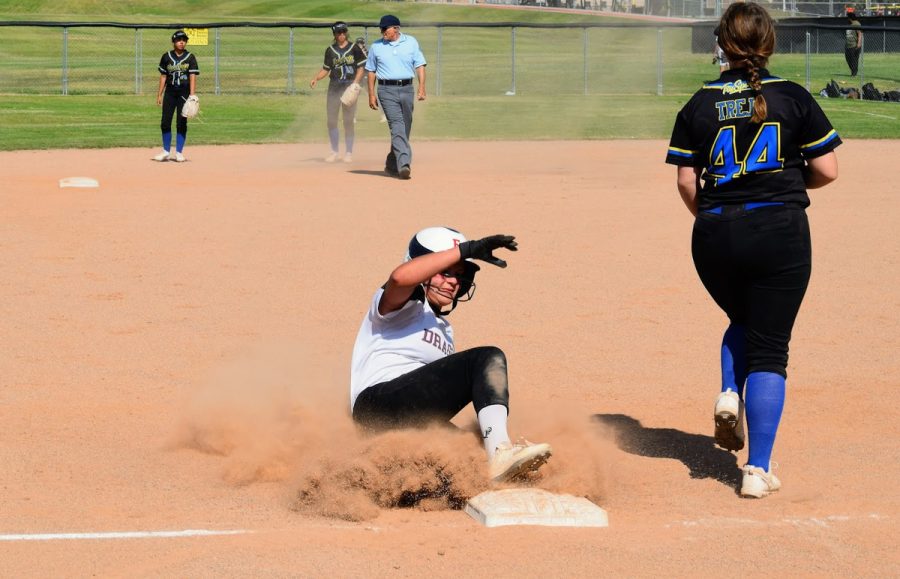 A cloud of sand sprays in the air as the Foothill Tech player successfully slides into third base.