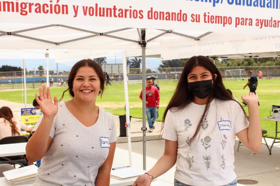 Two friendly volunteers smile welcomingly at those who approach their table.