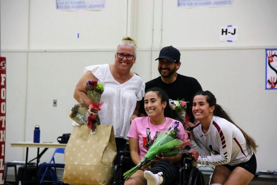 Adrianna and Isabella Rodriguez 23 pose with their parents, holding gifts honoring them on Senior Night.