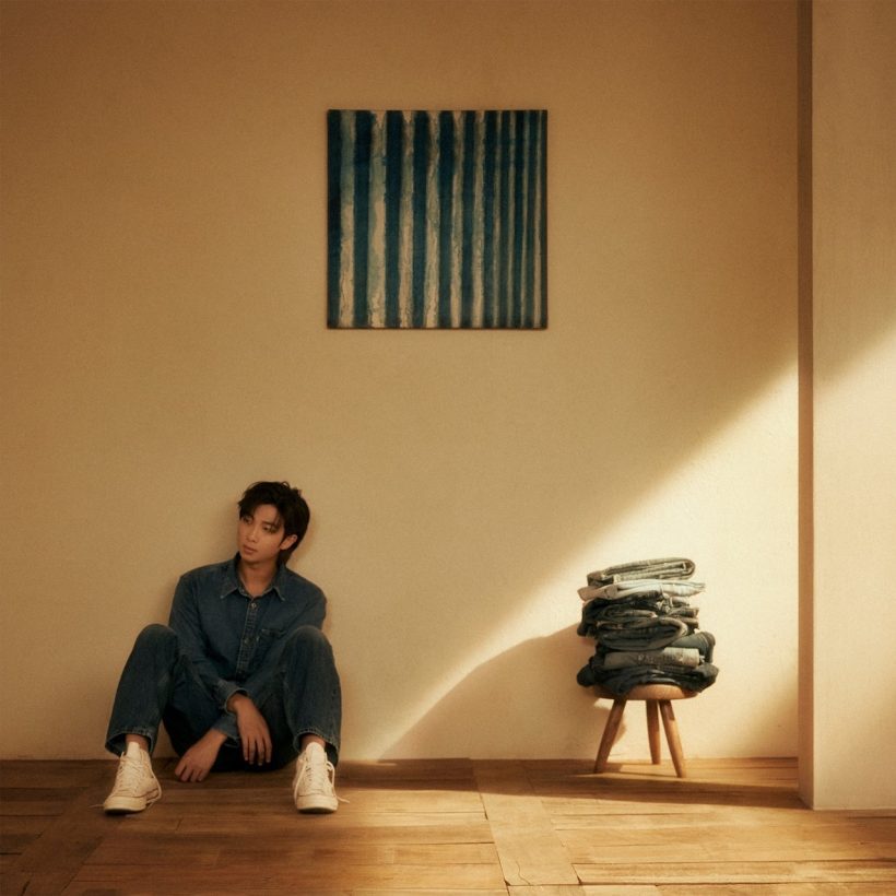 On the cover of his debut solo album “Indigo,” rapper-songwriter RM appears to be lost in thought as he sits beneath Dansaekhwa painter Yun Hyong-keun’s “Blue.” The late Korean modernist was one of RM’s biggest inspirations behind his December 2022 album. To the right, a pile of jeans rests atop a stool, symbolic of the worn-down love and warmth the rapper feels for his passing twenties.