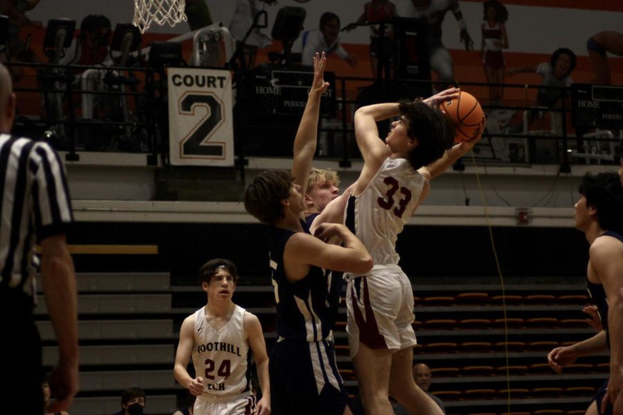 During the first half of the game, Sam Noah 23 (number 33) fights through two defenders, trying to get to the basket to make the shot. He was fouled midair and then had to shoot two free throws.