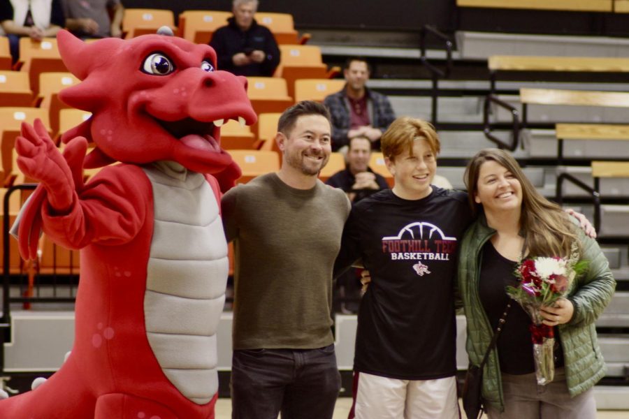 On Jan. 31, 2023, the boys basketball team gathered together to celebrate their seniors in a game against Laguna Blanca. In the photo, Owen Houston 23 hugs his parents as they pose for a photo with the dragon mascot during the senior ceremony. 