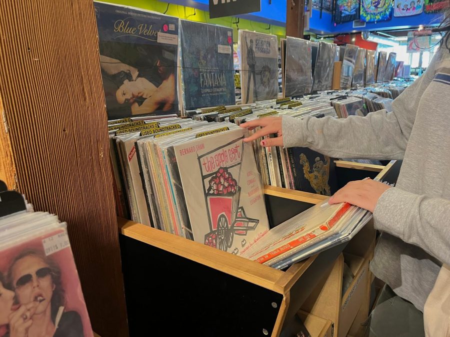 Ruby Jenkins ‘25 flips through the vast selection of soundtracks, new and used, available at Salzer’s Records. Records pile up on selves, some even kept in drawers that are labeled by genre. The section that Jenkins browses is their used dollar vinyls, providing an inexpensive alternative to the growing prices of new vinyls. 
