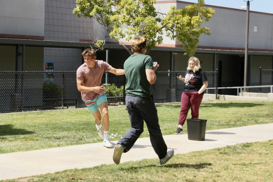 In a competition, two students race to move as many plastic balls from one side of the quad to the other. As the timer continues, their cheering classmates watch in anticipation, looking for winning score. This engaging activity provides an exciting way for students to learn and understand the curriculum of the class.