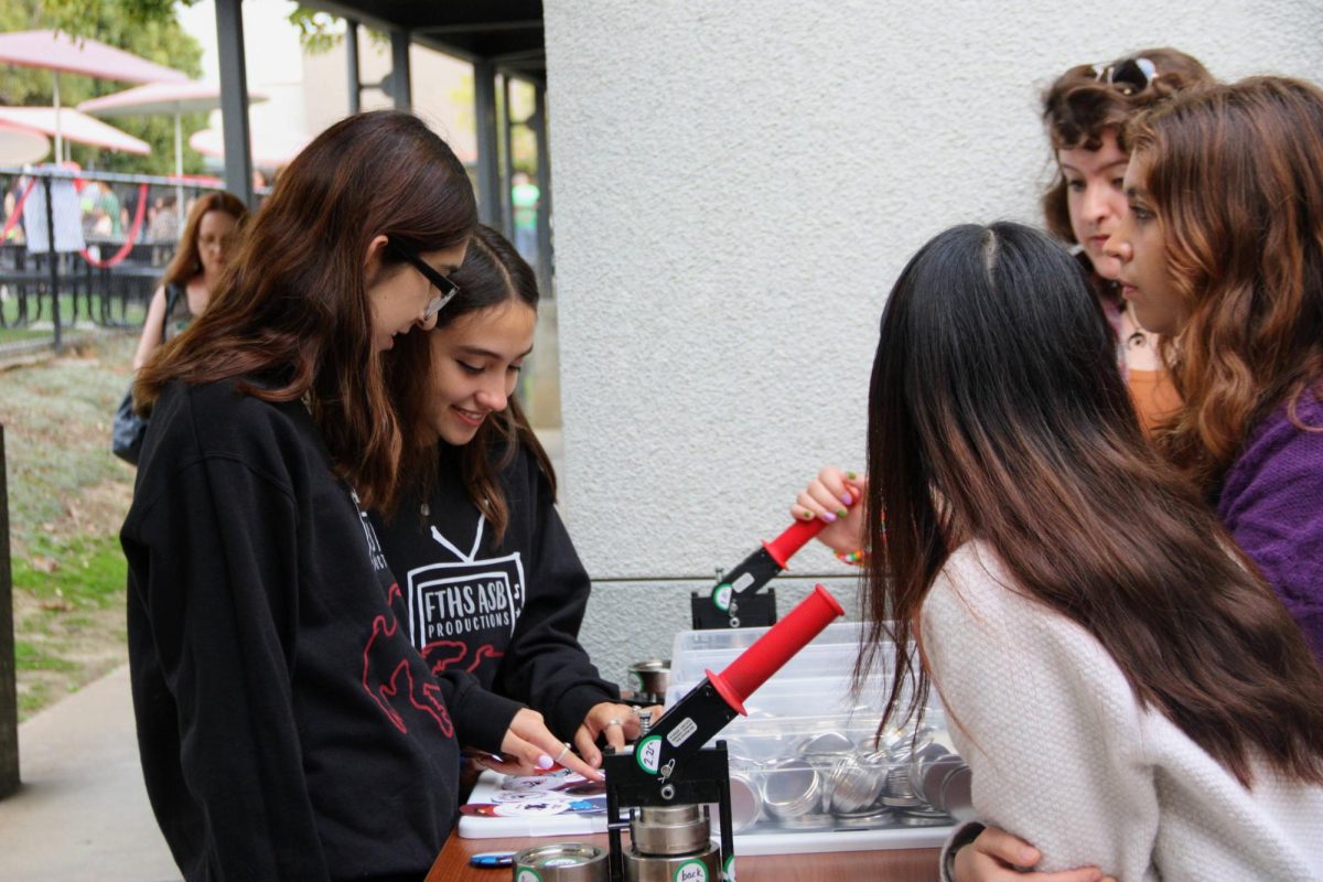 Students of Foothill Tech try to make button pins of their own design at Back to School Night. This college and career class provides an opportunity to learn life skills and creativity.