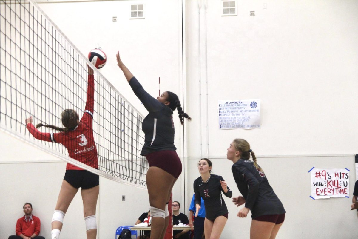 Channing McClure 25 (number 14) cleverly times her block, jumping in the air perfectly with Bishop Diego, denying them as they attempt to score a point.