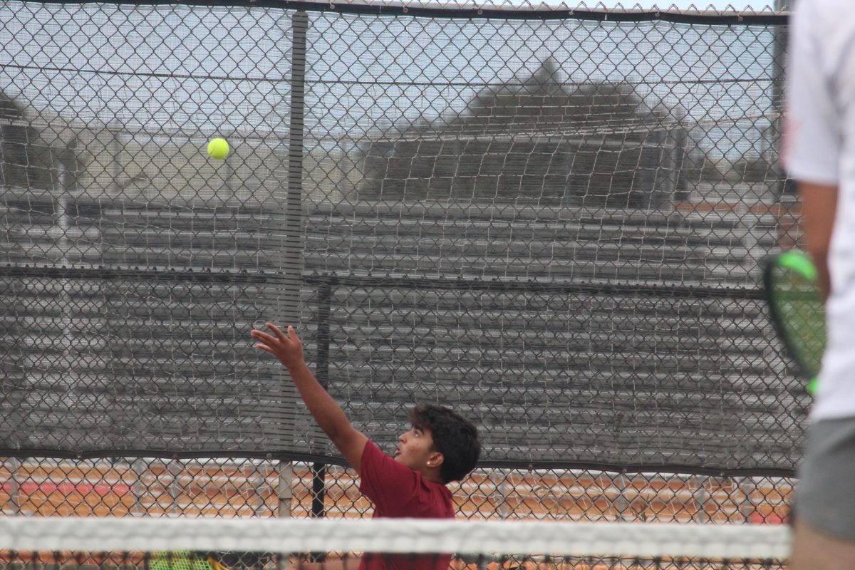 Ansh Joshi 26 tosses the tennis ball in the air in preparation for his serve. Joshi and his teammate Aadi Ramalingam 27 won two of the three sets they played.