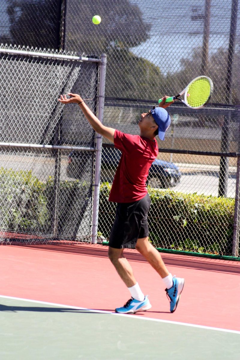 Shaurya Shyam 25 tosses the ball in the air for his serve.