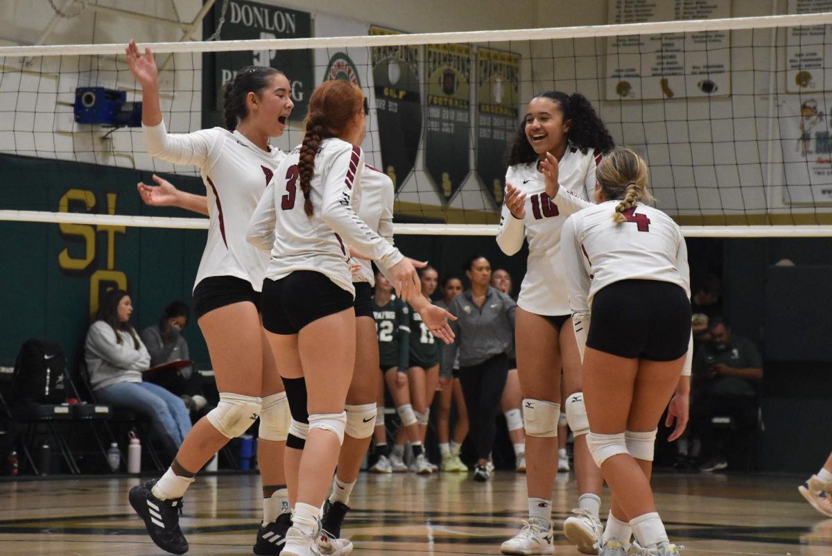 Fiona Holt '28 (number 8), Aliana Hantgin '25 (number 3), Emily Turner '26 (number 4) and Maya Adams '28 (number 10) once again celebrate a fatiguing rally after securing a point with a tip over the net, while the rival team unsuccessfully saved the ball from hitting the ground.