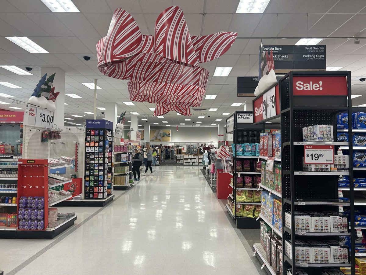 Target is rolling out its annual Christmas holiday decorations with posters sitting on top of every aisle. Shoppers are surrounded by trees and snowman cutouts as well as a Christmas stripes hanging from the ceiling giving a cheerful shopping atmosphere.