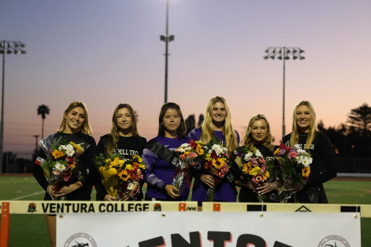 Six seniors stand side by side on the field for senior night, each holding a bouquet of flowers and proudly wearing their jerseys. Surrounded by their teammates, they take a moment to reflect on their years of hard work and dedication to the sport, as the crowd cheers in appreciation of their accomplishments.