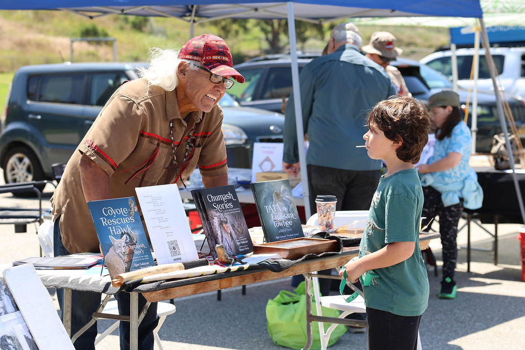 Alan Salazar, depicted here, was one of the many exhibitors at Ventura Charter School's EcoFest. The ring of booths around the event contained information about topics ranging from Native American folklore, like Salazar is advertising here, to replacing oil and gas with more sustainable energy sources. 