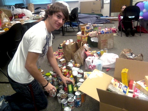 Junior Trevor Kirby organizes canned food donated by students for the Cheers for Children food drive. Credit: Caitlin Trude/The Foothill Dragon Press.