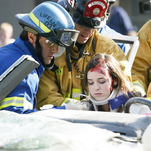 aSenior Marnie Vaughan, who played the part of a critically injured victim in the simulation, is pulled out of a vehicle by firemen. Credit: Aysen Tan/The Foothill Dragon Press