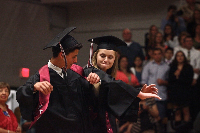 Seniors Maelynn Dickson and Brandon Carrasco bump hips before taking their seats at graduation. Credit: Aysen Tan/The Foothill Dragon Press