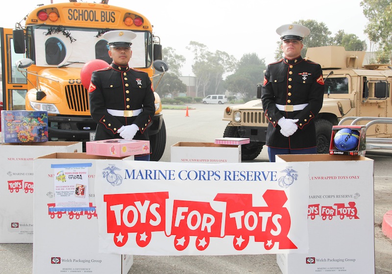 Two marines who volunteered for Toys for Tots stand in front of the bus stuffed on Saturday. Credit: Lauren Pedersen/The Foothill Dragon Press